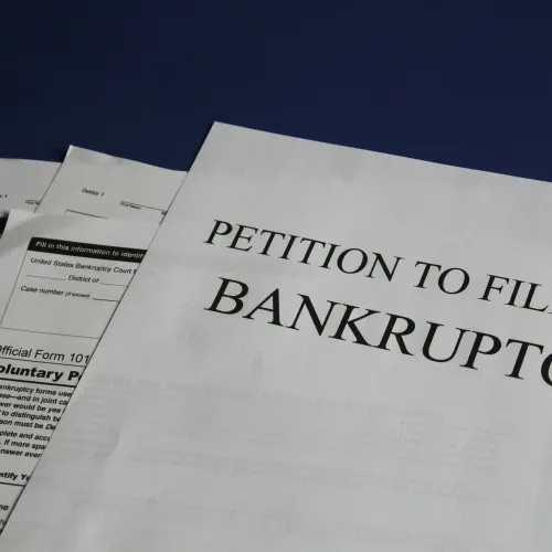 Close-up of printed documents titled Petition to File for Bankruptcy on a dark blue background.