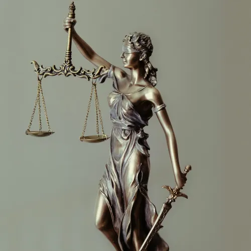 Bronze statue of Lady Justice holding scales and sword, symbolizing fairness and law enforcement.