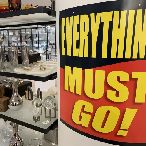 Retail store shelves with decorative items and a large sign reading Everything Must Go in bold yellow letters