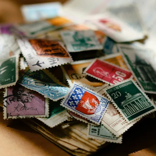 Collection of colorful vintage postage stamps scattered on an open book page with warm lighting.