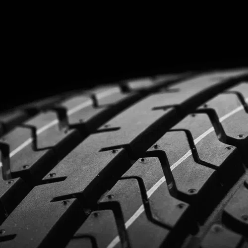 Close-up of black tire tread pattern with grooves showing detailed rubber texture on dark background