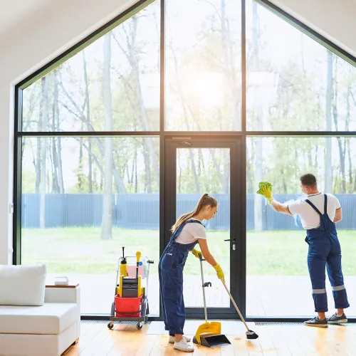 a man and a woman cleaning a room with a large glass door