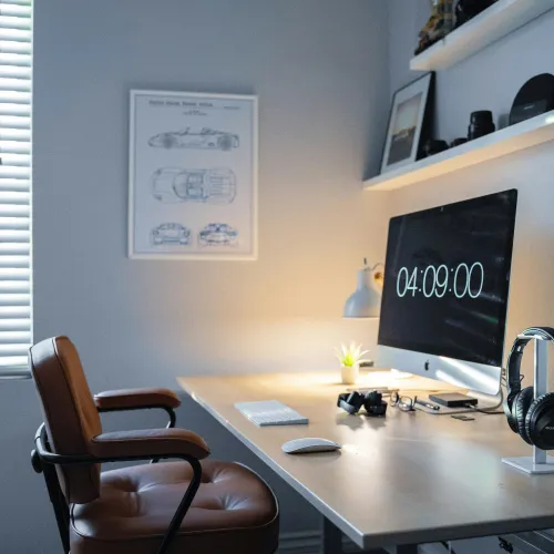 a desk with a computer and a chair in a room with a window