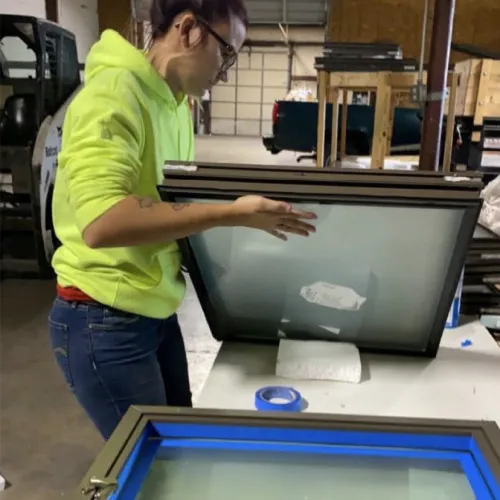 Person in a bright yellow hoodie working on framed screen printing frames in a workshop setting.