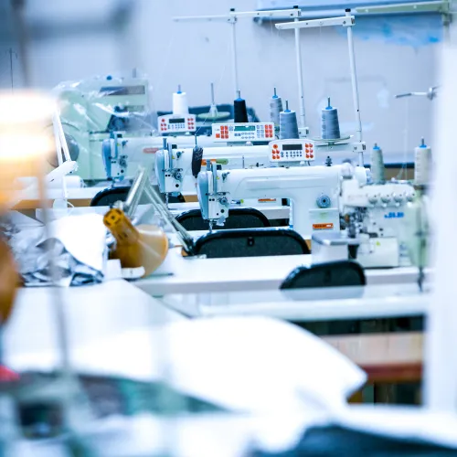 A sewing workshop filled with sewing machines and spools of thread, emphasizing textile production.