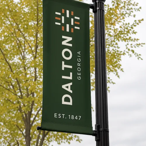 Green banner displaying the word 'DALTON' with tree and cloudy sky in the background.
