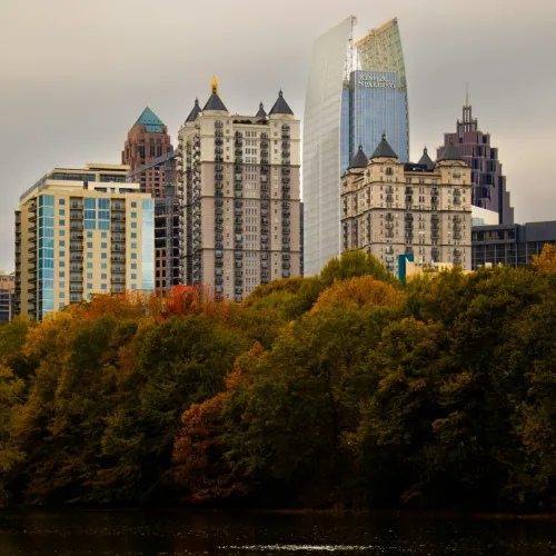 Atlanta city skyline with modern buildings behind trees showing autumn foliage by a body of water