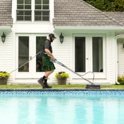 a man wearing a kilt and holding a golf club by a pool