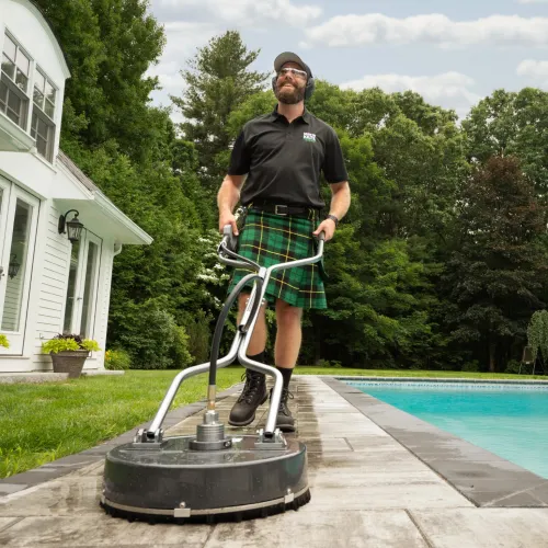 a man in a kilt using a surface washer