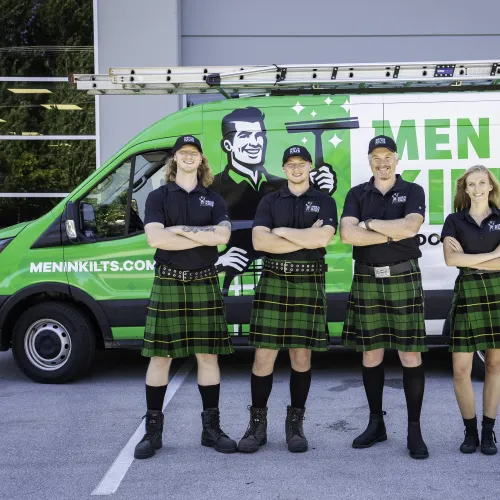 a group of people in kilts standing in front of a green van
