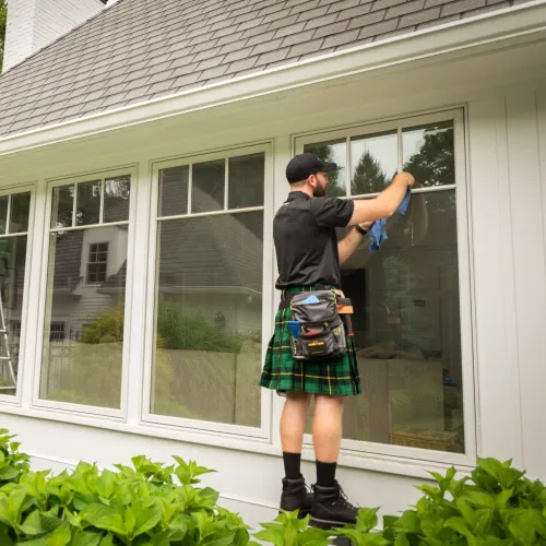 a person wearing a kilt and a hat standing outside a house