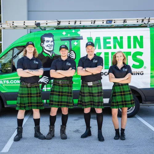 a group of people in kilts standing in front of a van