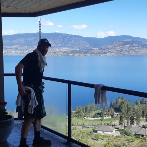 a man standing on a balcony overlooking a lake and mountains