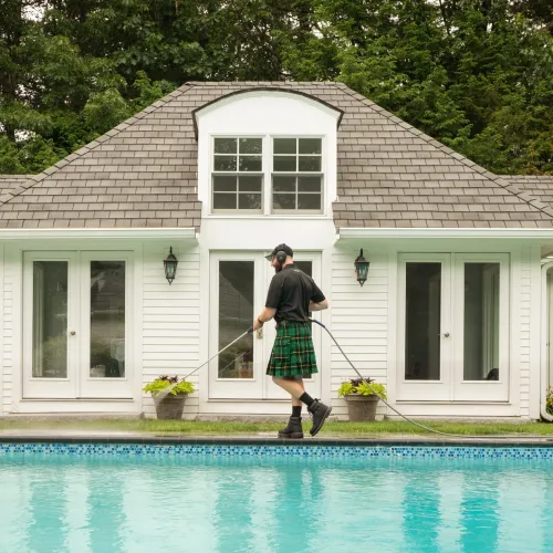 a person pressure washing beside a pool