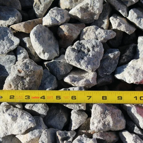 Yellow measuring tape extended over a pile of gray and brown rocks and gravel.