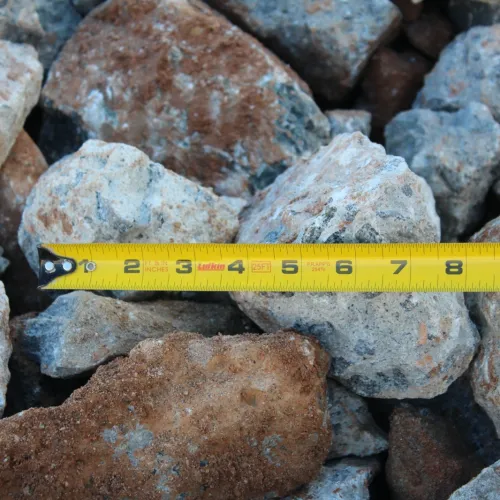 Yellow measuring tape placed on uneven rocks measuring their length outdoors.