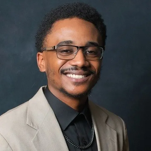 a man wearing glasses and smiling at the camera