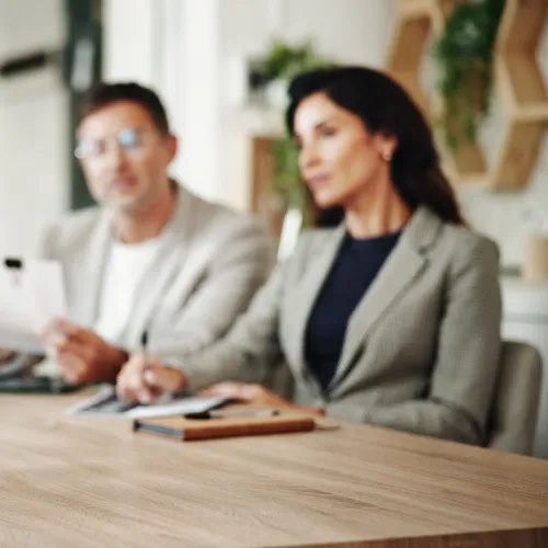 Woman in white blouse explaining to three colleagues during a business meeting around a wooden table.