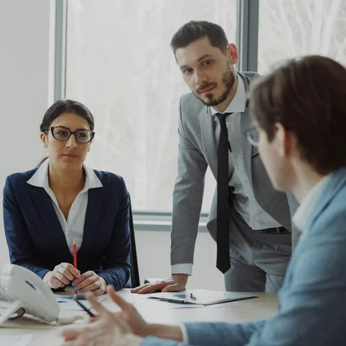 Four business professionals engaged in a meeting with computers and documents in a modern office setting.
