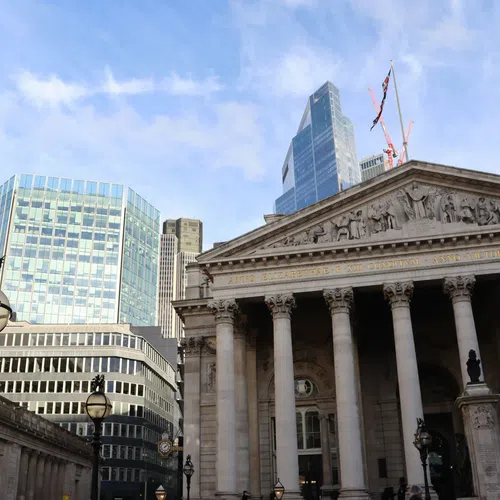 Historic neoclassical building with columns in London city with modern skyscrapers and blue sky background