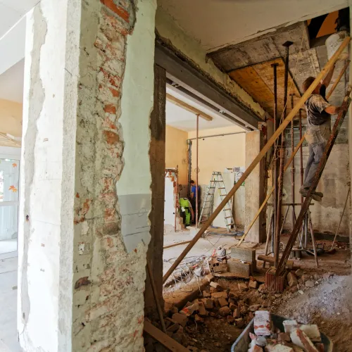 a person standing on a ladder in a room with debris all over