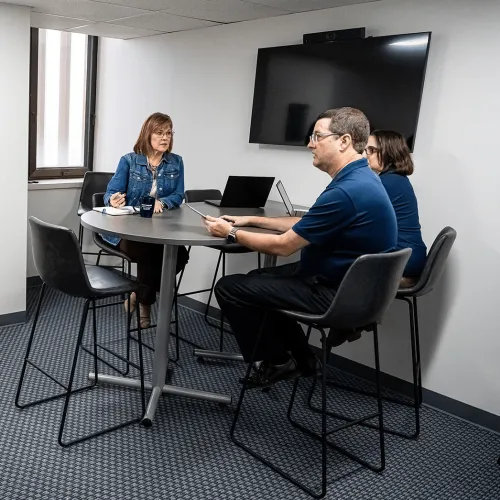 a group of people sitting at a table with laptops