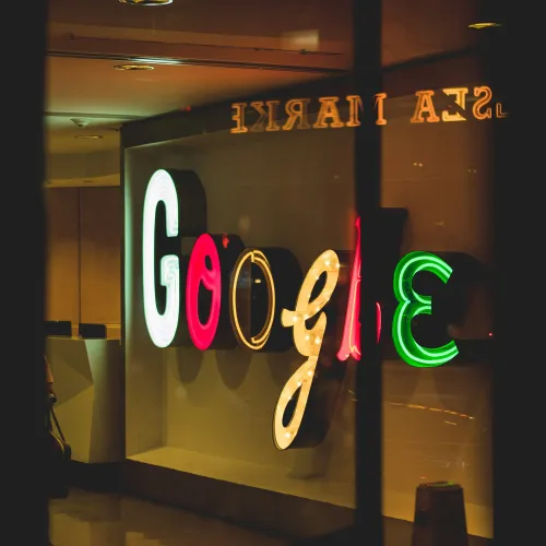 Illuminated Google logo sign with colorful letters displayed on an indoor wall.