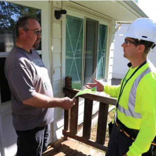 a man holding a rope to a man wearing a hard hat