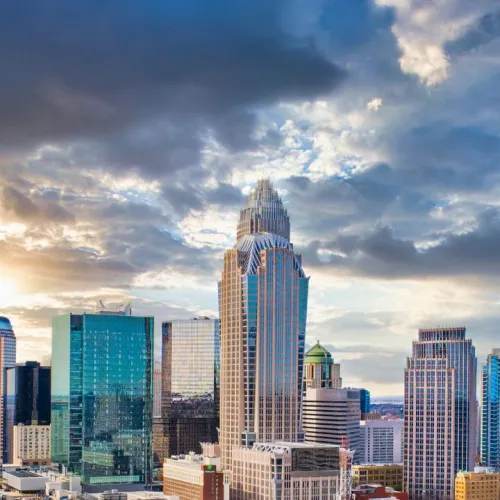 A stunning skyline view of Charlotte, North Carolina, featuring modern skyscrapers against a dramatic sky.
