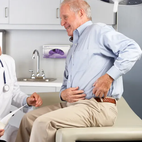 Doctor examining elderly male patient complaining of abdominal pain in medical office setting