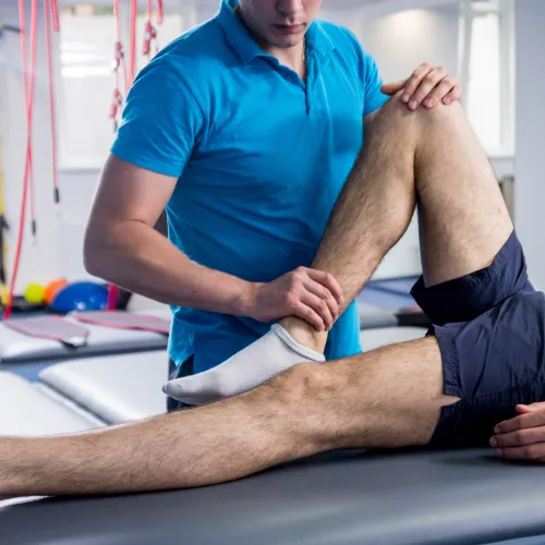 Physical therapist assisting a patient with leg stretching exercises in a rehabilitation clinic.