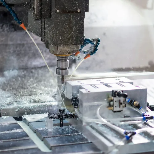 CNC milling machine cutting metal with coolant spraying and metal shavings scattered around the workspace