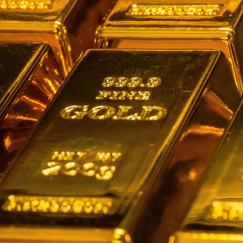 Close-up of shiny gold bars stacked together with inscriptions showing weight and purity details.