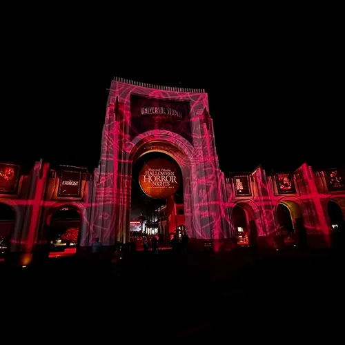 Universal Studios entrance lit with red lights for Halloween Horror Nights event at night.