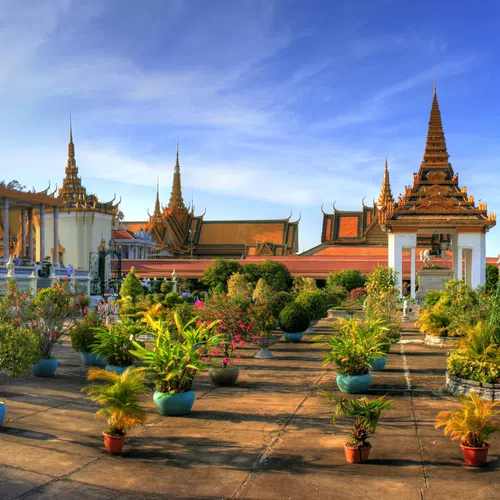 Panoramic view of a traditional temple complex with ornate roofs, statues, and lush greenery under a clear sky.