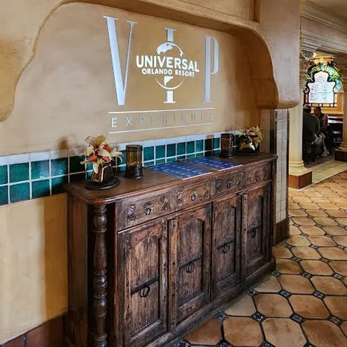 Rustic wooden cabinet under VIP Universal Orlando Resort Experience sign with tiled floor and wall decor.