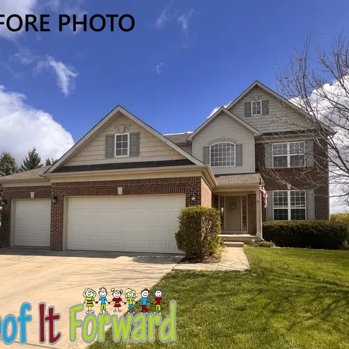 Two-story brick and siding house with a large driveway under a partly cloudy blue sky labeled before photo.