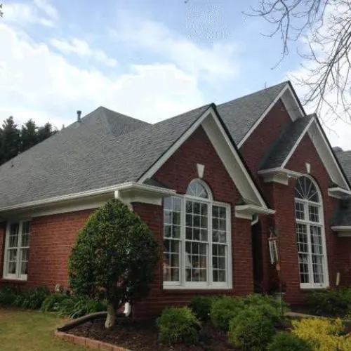 The side view of a house with a bush in front
