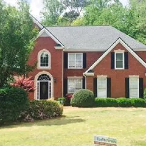 a large brick building with grass in front of a house