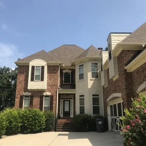 a house with bushes in front of a brick building