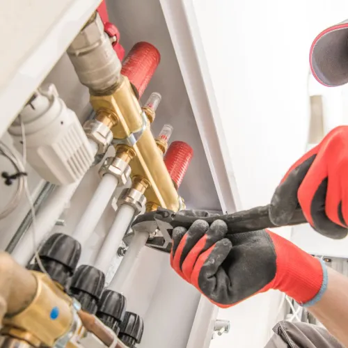 a man in a red hat and gloves working on a machine