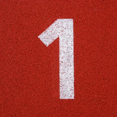 White number one painted on a red textured running track surface representing lane one.