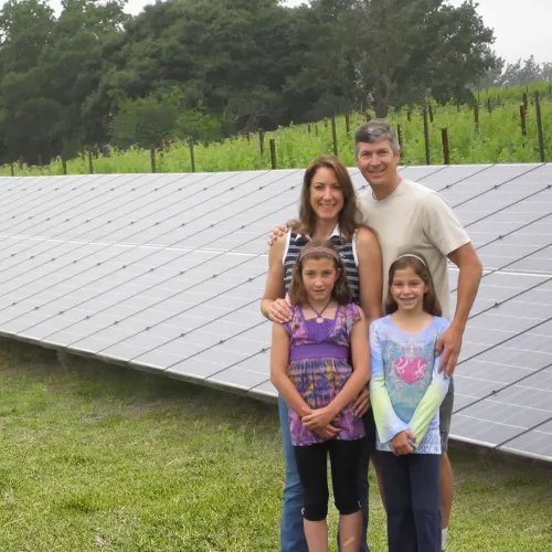 a group of people posing for a photo in front of a solar panel