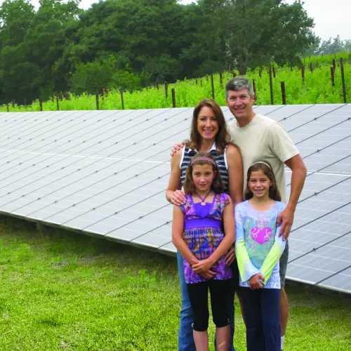 a group of people posing for a photo in front of a solar panel