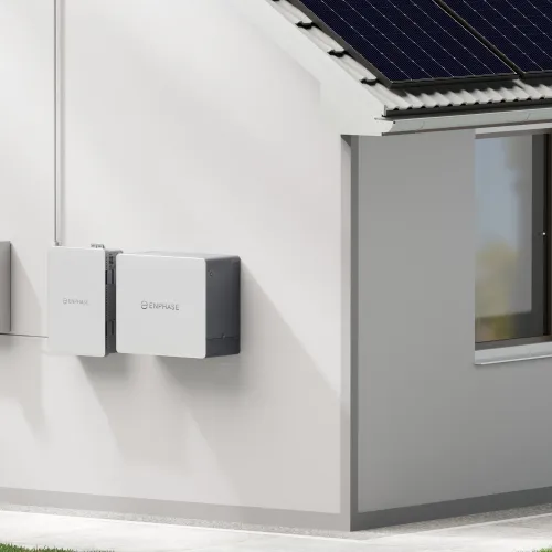 Solar panels on roof and battery storage units installed on white house exterior wall during daytime
