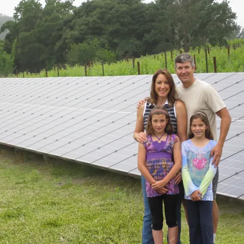 a group of people posing for a photo in front of a solar panel
