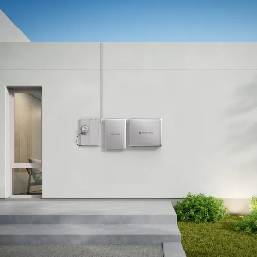 Modern white electric power storage system mounted on clean exterior wall of minimalist house under blue sky.