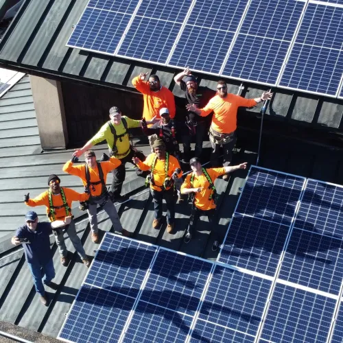 a group of people in orange jumpsuits on a roof with solar panels