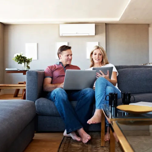 a man and a woman sitting on a couch with a laptop