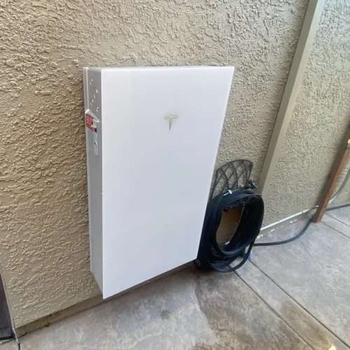 a white rectangular object with a black cord and a black bag on a tile floor